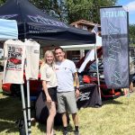 Two vendors standing in front of their canopy booth