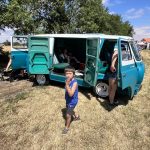 A child standing in front of a small van with the doors open