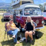 Two car show enthusiasts in front of their pop top VW camper van