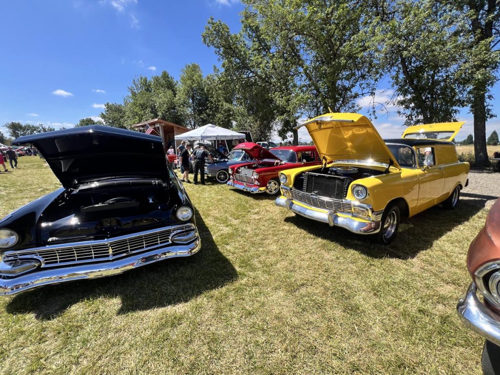 Various classic cars with hoods open to display engine